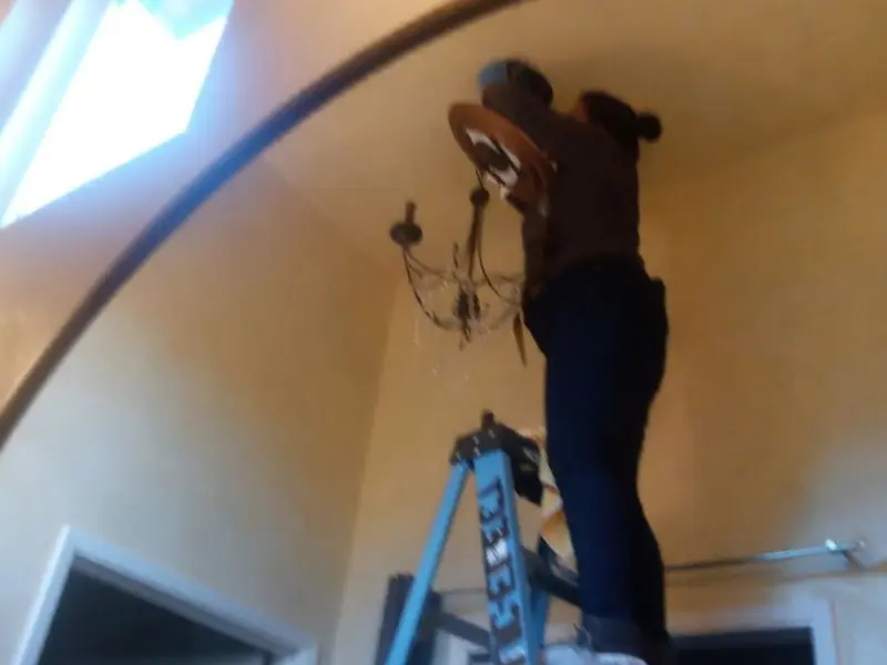 Electrician installing a chandelier in a Roswell residence